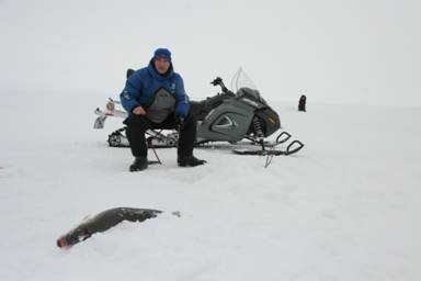 Patrick jigs for sheefish with Lori at another hole behind him!