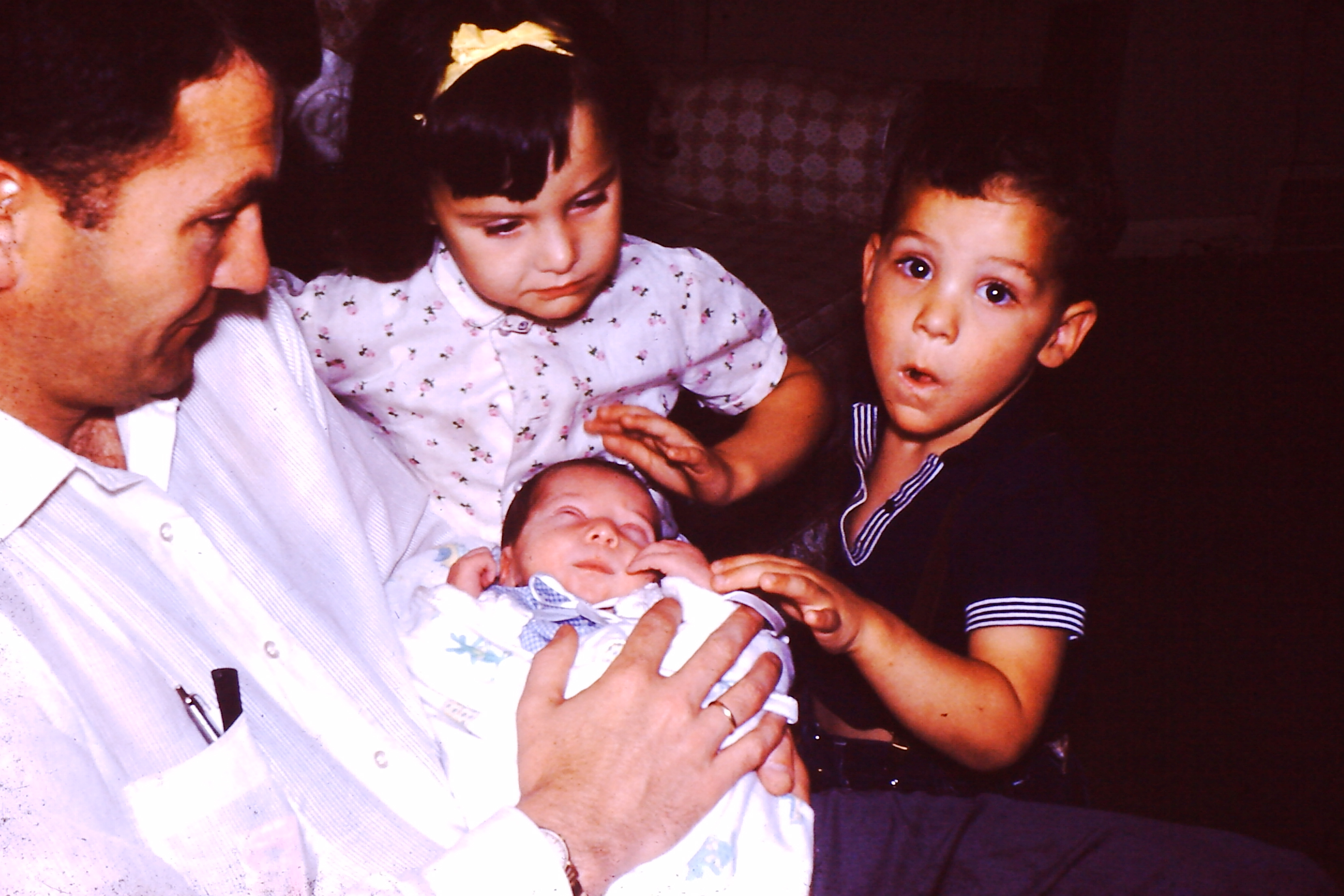 Gene holding a baby with Dodie and Jim looking on. Is the baby Chip? Pat? Dan?
